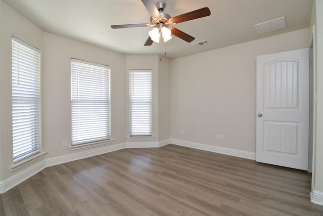 unfurnished room with a healthy amount of sunlight, hardwood / wood-style floors, and ceiling fan