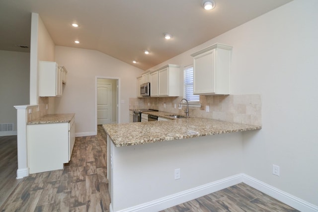 kitchen with white cabinetry, kitchen peninsula, sink, and light stone counters