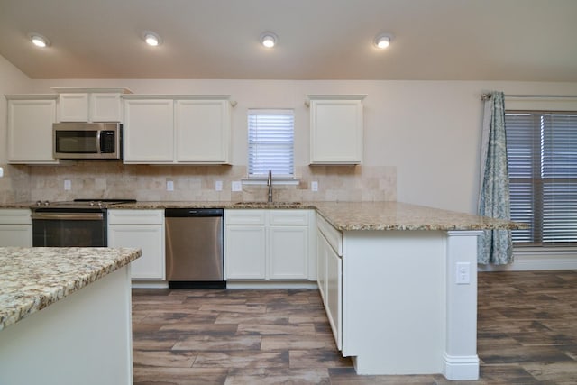 kitchen featuring stainless steel appliances, light stone countertops, sink, and white cabinets