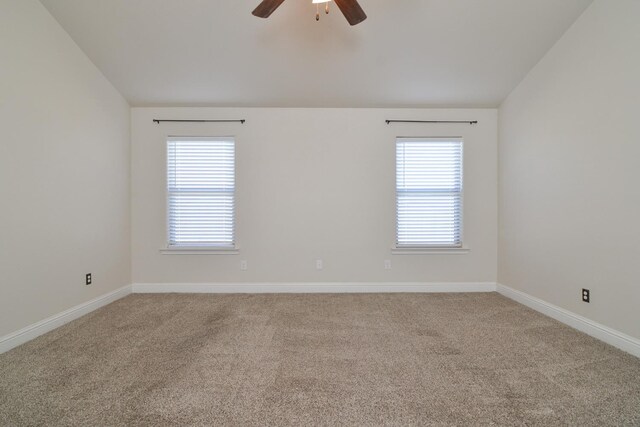 carpeted empty room with a wealth of natural light, ceiling fan, and vaulted ceiling