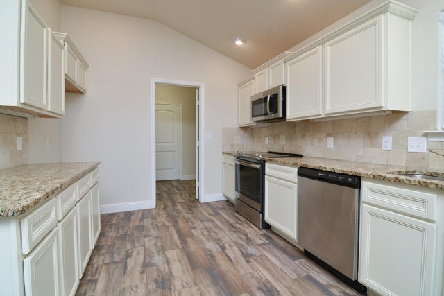 kitchen with white cabinetry, stainless steel appliances, and light stone counters