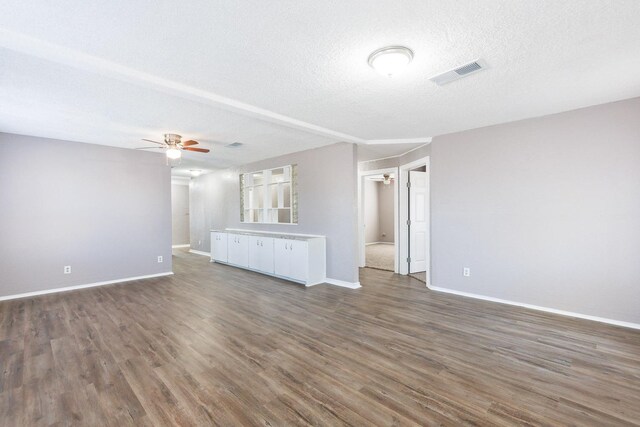 unfurnished living room with ceiling fan, dark hardwood / wood-style flooring, and a textured ceiling