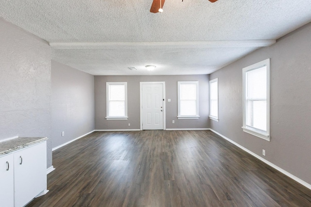 unfurnished living room featuring dark hardwood / wood-style floors, a textured ceiling, and ceiling fan