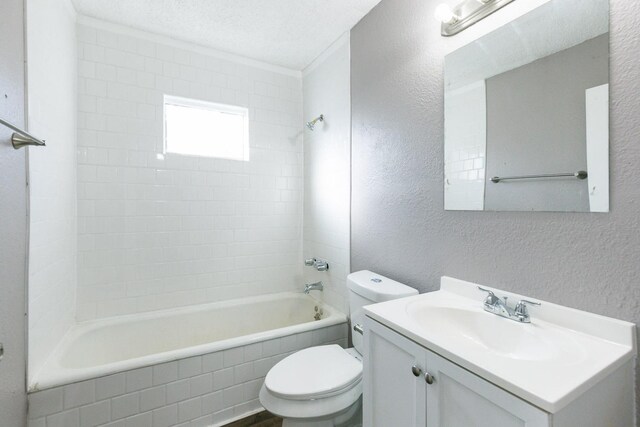 full bathroom with vanity, toilet, tiled shower / bath combo, and a textured ceiling