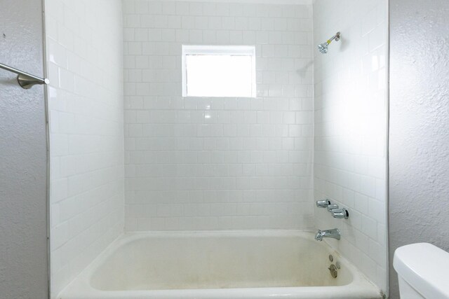 bathroom featuring tiled shower / bath and toilet