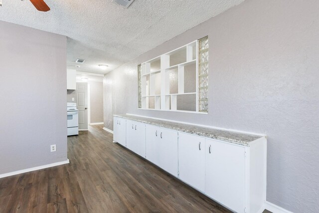 interior space with stove, dark wood-type flooring, white cabinets, and a textured ceiling