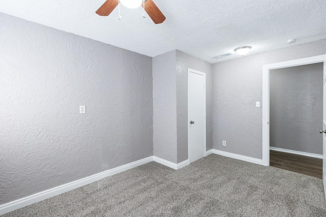 empty room featuring ceiling fan, carpet floors, and a textured ceiling