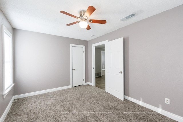 unfurnished room featuring ceiling fan and carpet