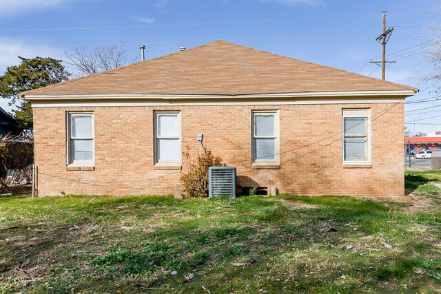 back of property with central AC unit and a lawn