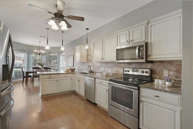 kitchen with tasteful backsplash, hanging light fixtures, stainless steel appliances, and kitchen peninsula