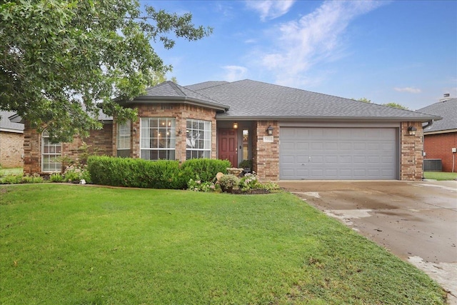 view of front of property featuring a garage, a front yard, and central AC unit