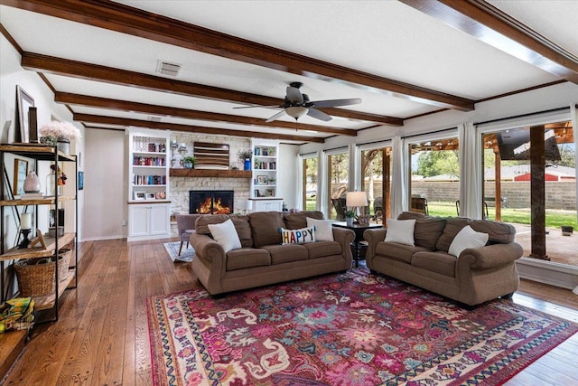 living room featuring beam ceiling, hardwood / wood-style flooring, a fireplace, and ceiling fan