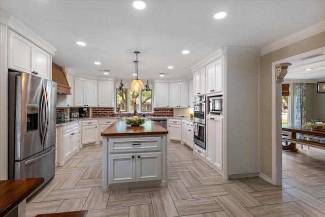 kitchen featuring pendant lighting, wooden counters, appliances with stainless steel finishes, a center island, and white cabinets