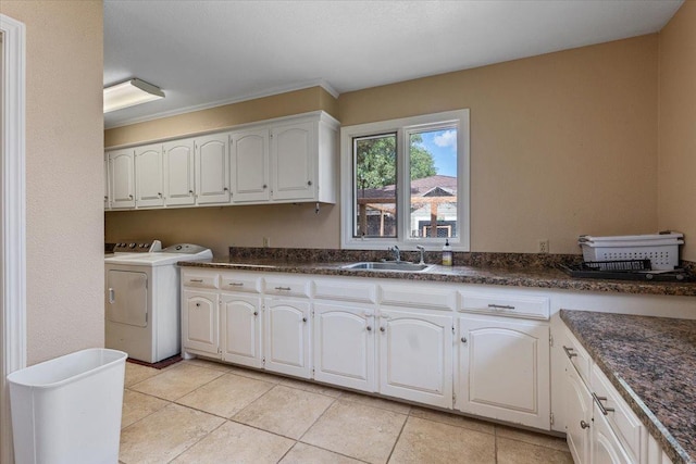 kitchen with separate washer and dryer, sink, light tile patterned floors, and white cabinets