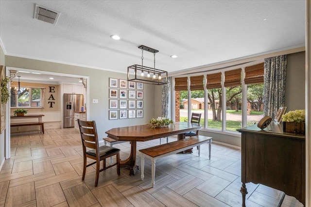 dining area featuring crown molding, a textured ceiling, a chandelier, and light parquet flooring