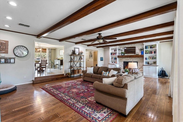 living room featuring beamed ceiling, a fireplace, dark hardwood / wood-style flooring, and ceiling fan