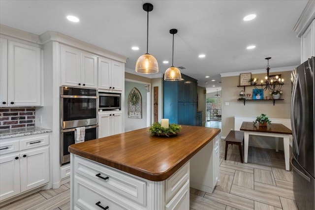 kitchen with hanging light fixtures, stainless steel appliances, white cabinets, and a kitchen island