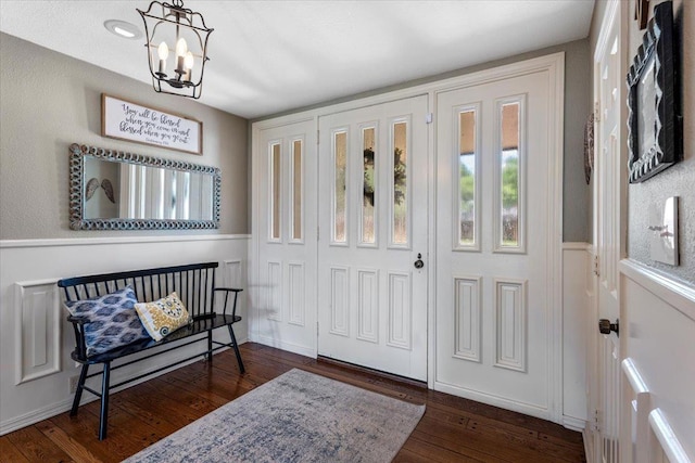 entryway with dark hardwood / wood-style floors and a notable chandelier