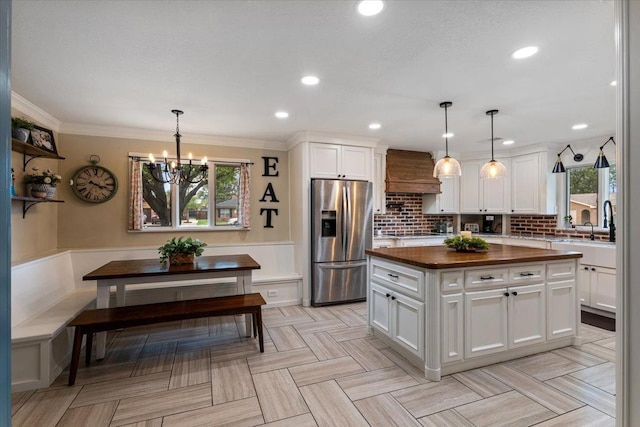 kitchen with pendant lighting, stainless steel fridge with ice dispenser, white cabinets, and breakfast area