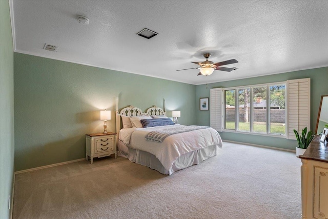 carpeted bedroom with ceiling fan, ornamental molding, and a textured ceiling