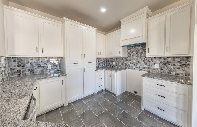 kitchen with tasteful backsplash, light stone countertops, and white cabinets