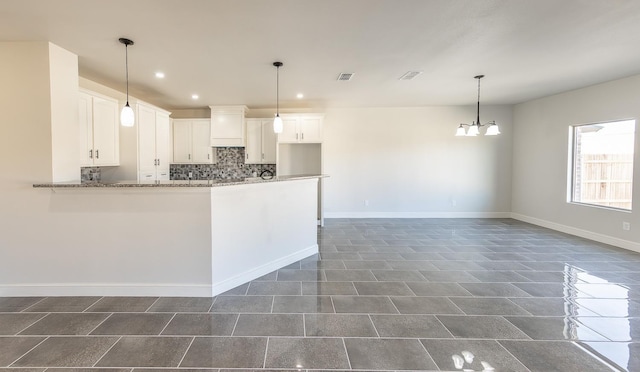 kitchen with stone countertops, white cabinetry, decorative backsplash, hanging light fixtures, and a notable chandelier