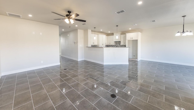 unfurnished living room featuring ceiling fan with notable chandelier