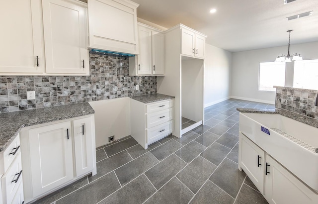 kitchen with tasteful backsplash, a notable chandelier, white cabinets, decorative light fixtures, and dark stone counters