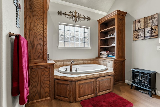 10801 Richmond Ave, Lubbock, TX 79424 - full bath featuring a textured ceiling, wood finished floors, vaulted ceiling, a wood stove, and a garden tub