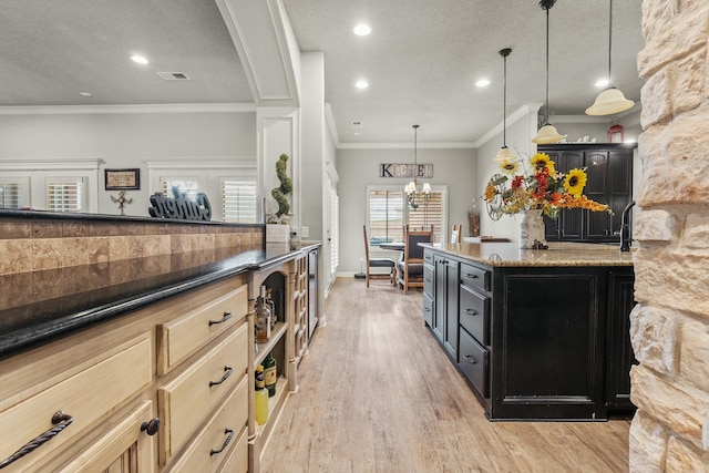 10801 Richmond Ave, Lubbock, TX 79424 - kitchen featuring light wood-style flooring, ornamental molding, dark stone counters, dark cabinets, and an inviting chandelier