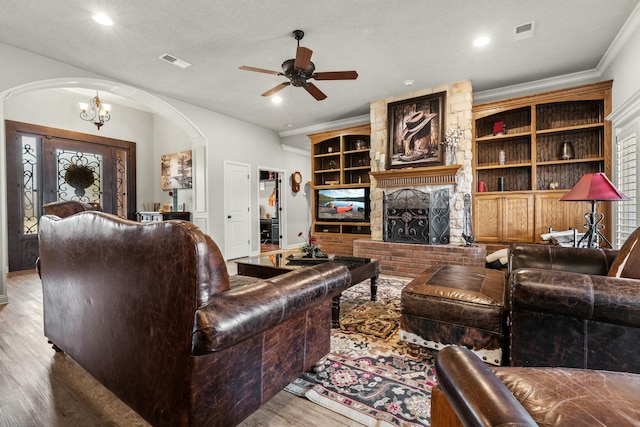 10801 Richmond Ave, Lubbock, TX 79424 - living room featuring wood finished floors, a brick fireplace, visible vents, arched walkways, and ceiling fan