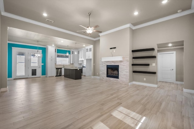 unfurnished living room featuring ceiling fan, ornamental molding, a fireplace, and light hardwood / wood-style floors