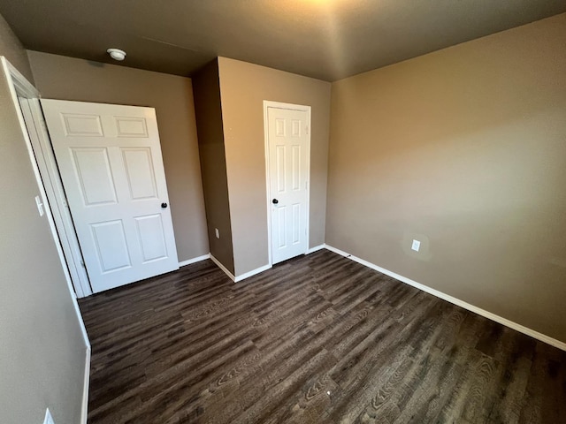 unfurnished bedroom featuring dark wood-type flooring and a closet