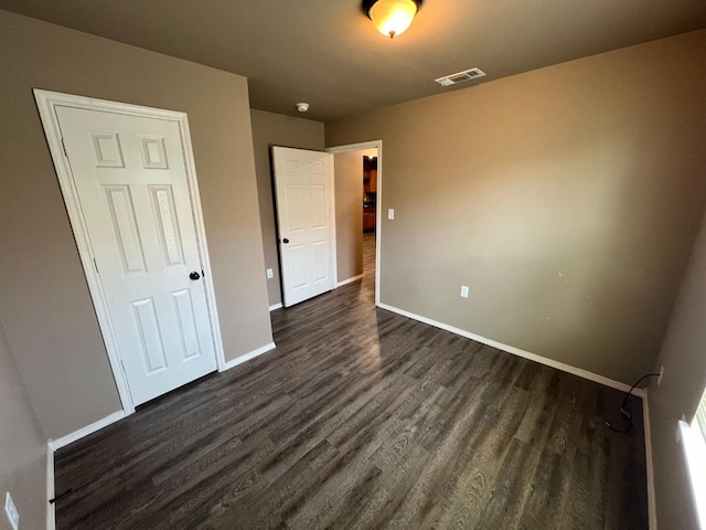 unfurnished bedroom with dark hardwood / wood-style flooring and a closet