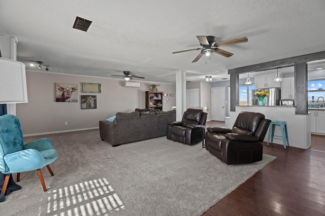 living room featuring ceiling fan, a wall mounted air conditioner, dark hardwood / wood-style floors, and a textured ceiling