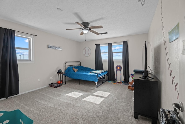 carpeted bedroom with ceiling fan and a textured ceiling