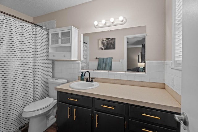 bathroom with vanity, toilet, a textured ceiling, and walk in shower