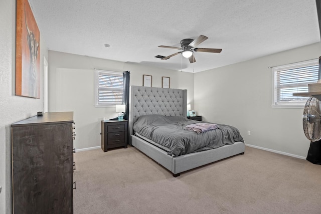 bedroom featuring multiple windows, a textured ceiling, light carpet, and ceiling fan