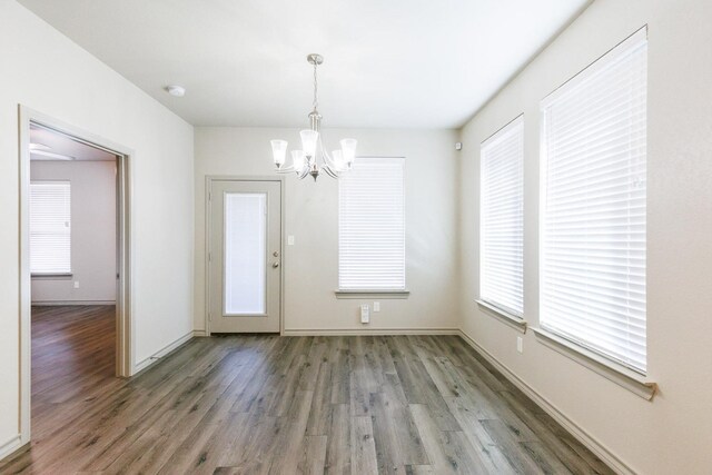 unfurnished dining area featuring dark hardwood / wood-style floors and a notable chandelier