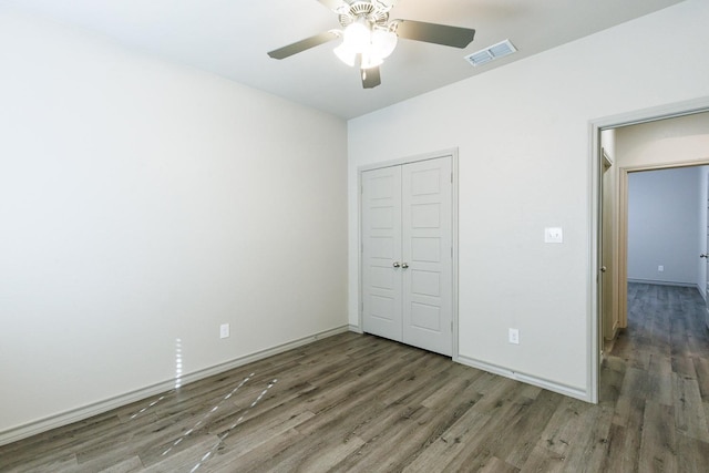 unfurnished bedroom with ceiling fan, dark hardwood / wood-style flooring, and a closet