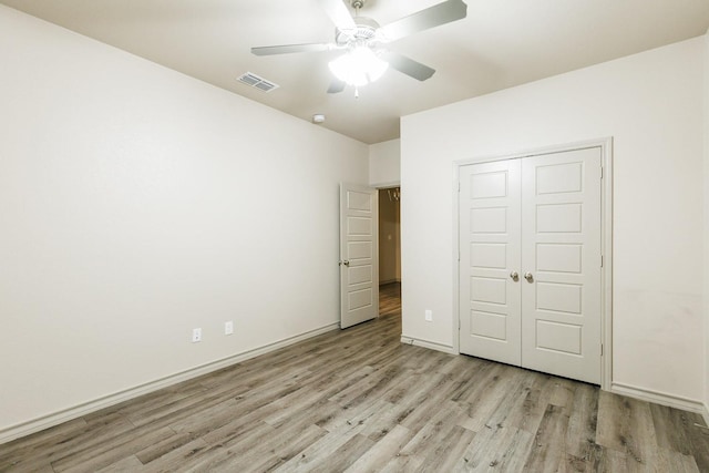 unfurnished bedroom featuring ceiling fan, a closet, and light hardwood / wood-style flooring