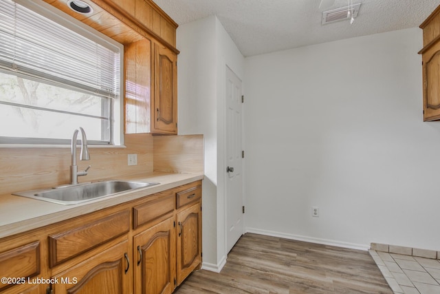 1804 E Hester St, Brownfield, TX 79316 - kitchen with a sink, light countertops, light wood-type flooring, brown cabinets, and a textured ceiling