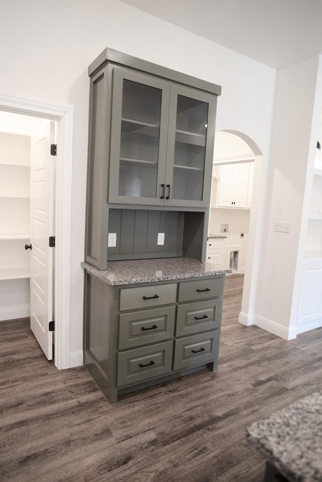 bar featuring dark hardwood / wood-style floors, gray cabinets, and stone counters