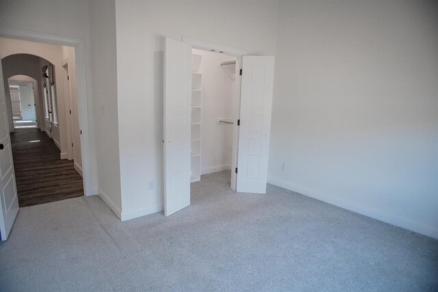 unfurnished bedroom with a spacious closet, carpet floors, and a closet