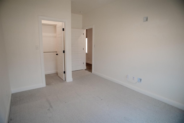 unfurnished bedroom featuring light colored carpet, a spacious closet, and a closet