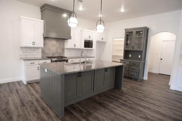 kitchen with white cabinetry, premium range hood, sink, and dark stone countertops