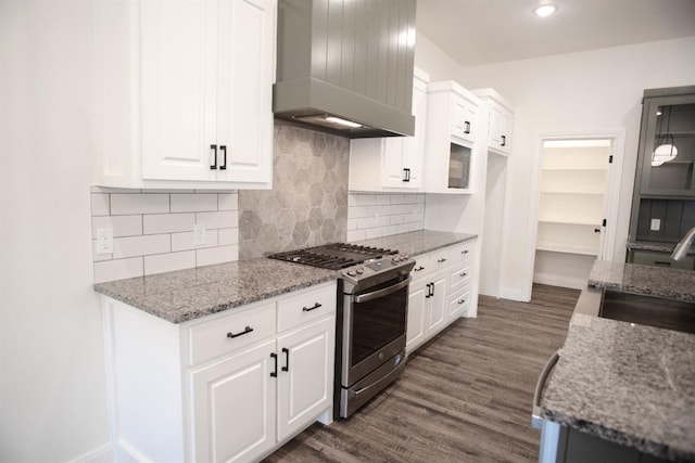 kitchen with white cabinetry, sink, gas range, light stone countertops, and wall chimney range hood