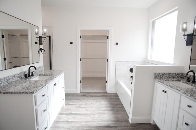 bathroom featuring vanity, hardwood / wood-style floors, and a tub to relax in