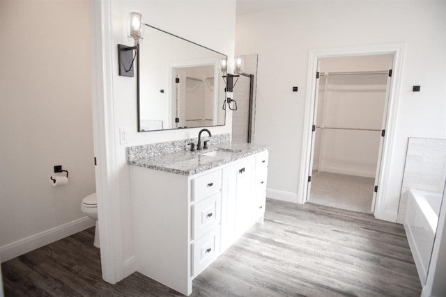 bathroom featuring vanity, hardwood / wood-style floors, a washtub, and toilet