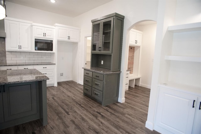 kitchen featuring dark stone countertops, dark hardwood / wood-style flooring, black microwave, and white cabinets